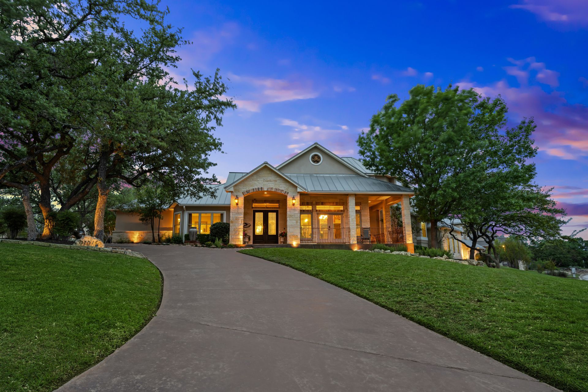 A large house is sitting on top of a lush green hill.