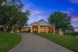 A large house is sitting on top of a lush green hill.