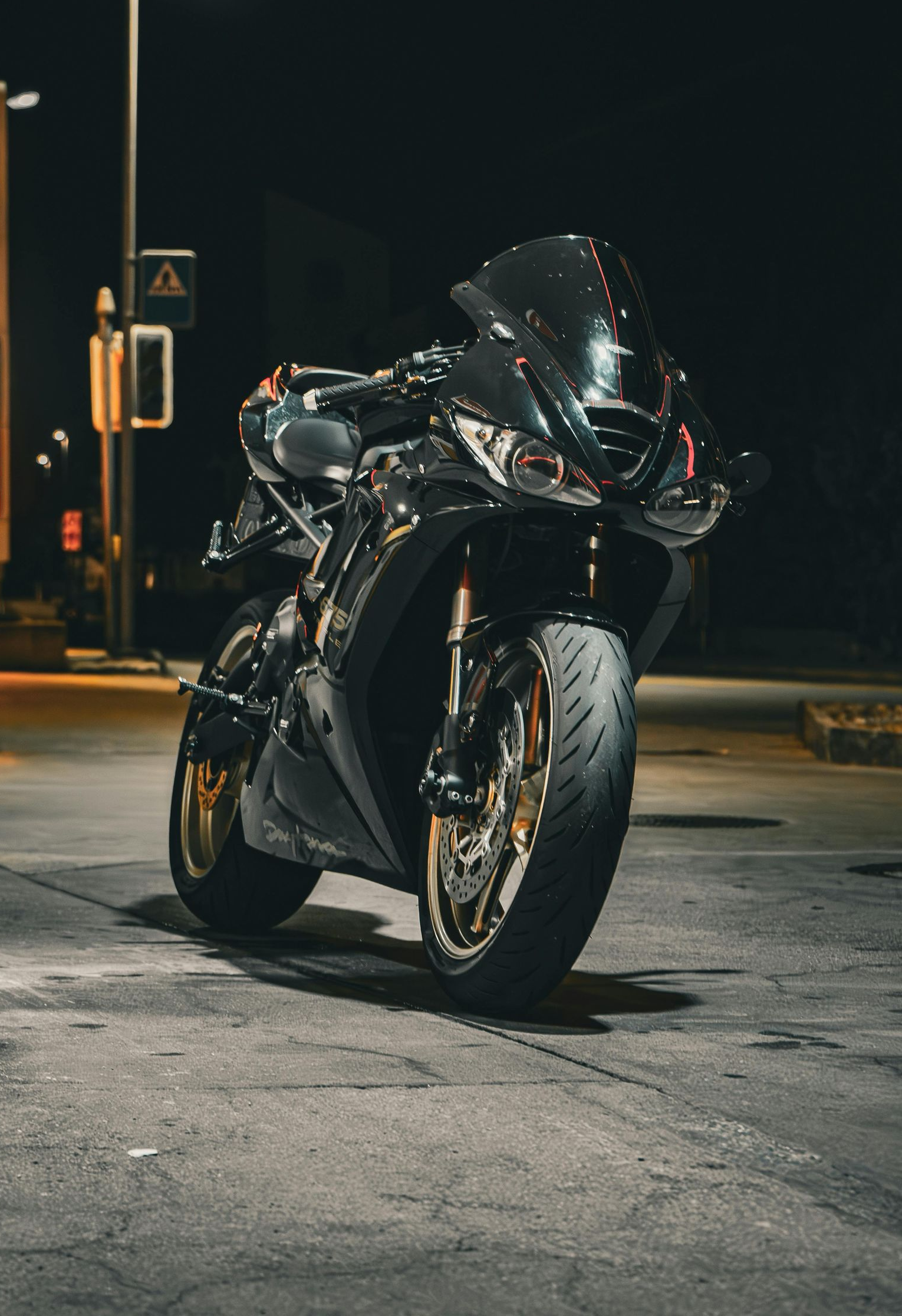 Black sport motorcycle parked at night, gold wheels, lit by streetlights. — Geelong Accident Towing & Recovery Centre In North Geelong, VIC