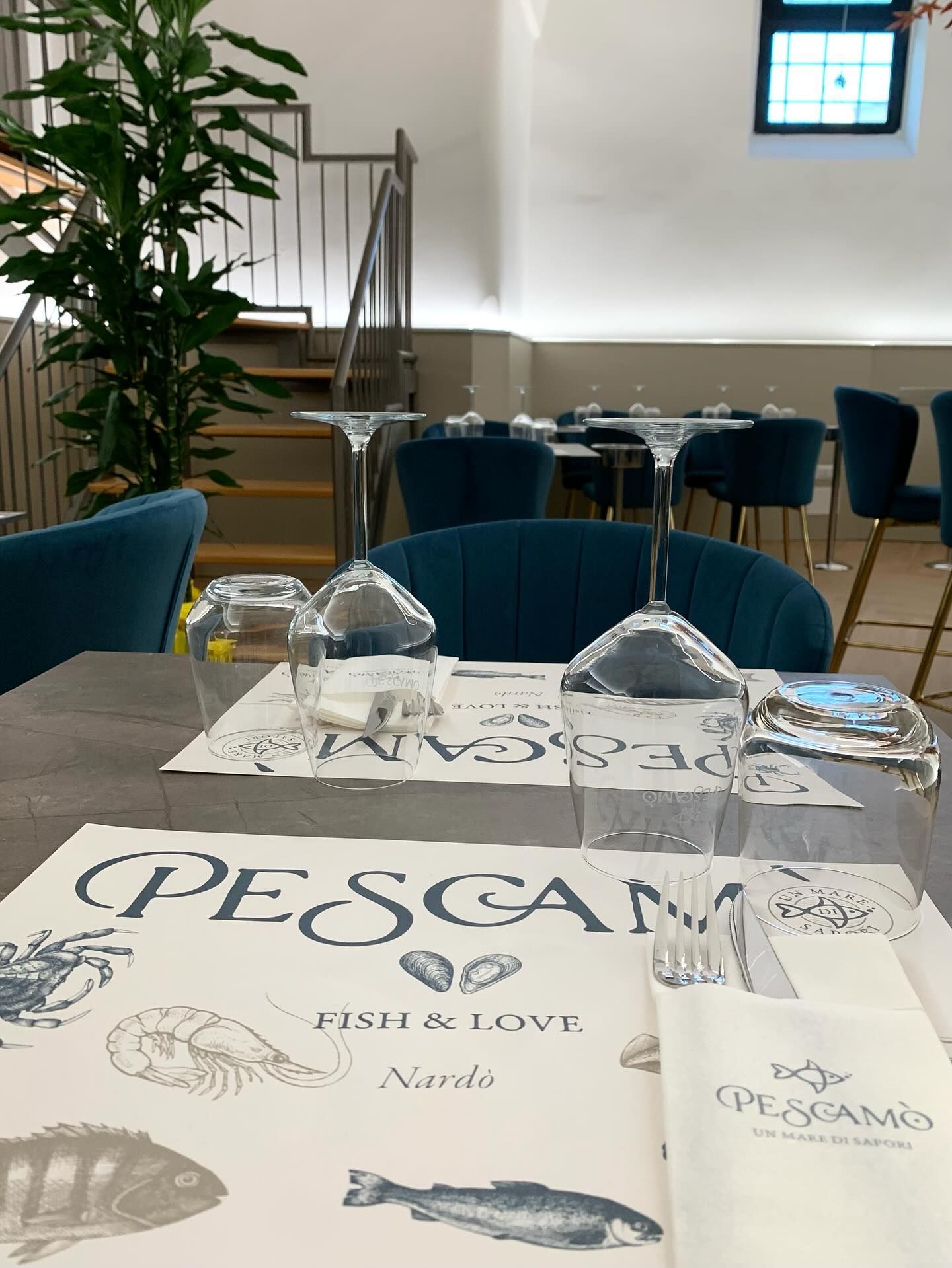 Piatto di frutti di mare con limoni e arance su un tavolo; bottiglie e bicchiere di vino sullo sfondo.