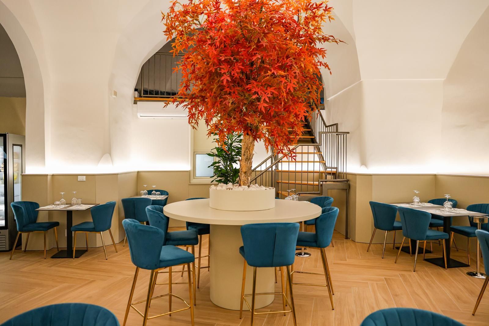 Un bicchiere di vino e una bottiglia su un tavolo. Il bicchiere è pieno di vino rosso. L'etichetta della bottiglia raffigura dei fiori blu.