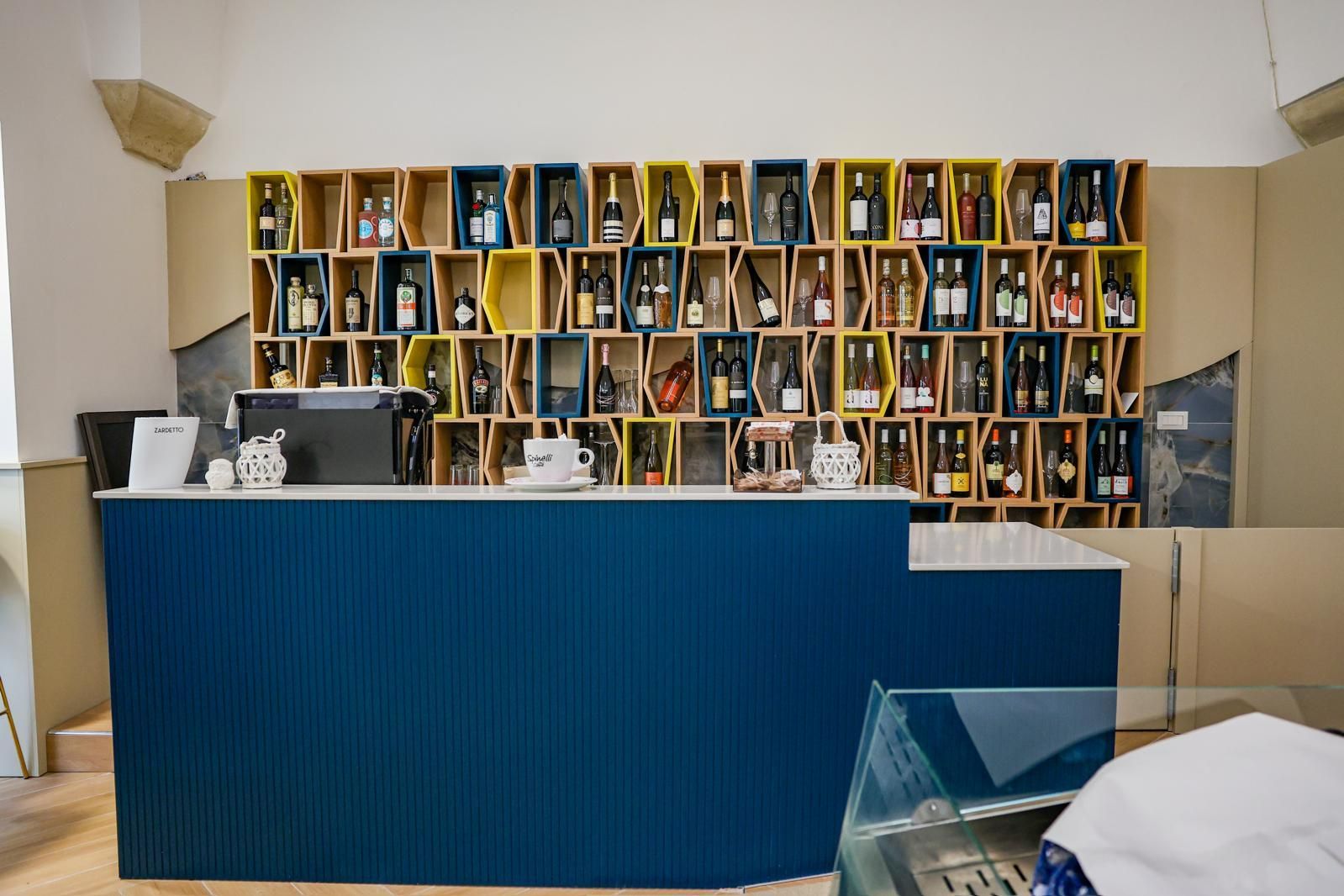 Uomo che suona il violino su una strada acciottolata di notte; persone che cenano in un bar all'aperto.