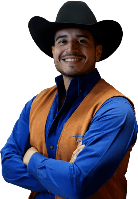 Man in cowboy hat, blue shirt, and brown vest smiling, arms crossed.