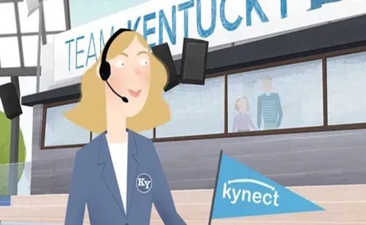 Woman in blue blazer wearing a headset stands in a Kynect booth with a Kentucky sign behind her.