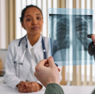 Doctor reviewing a chest X-ray held up in a clinic office