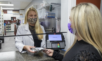 Pharmacist handing medicine to a customer across a pharmacy counter