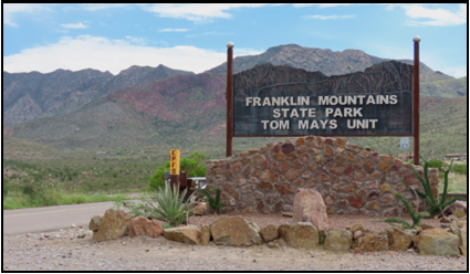 A sign for franklin mountains state park is sitting on top of a stone wall.