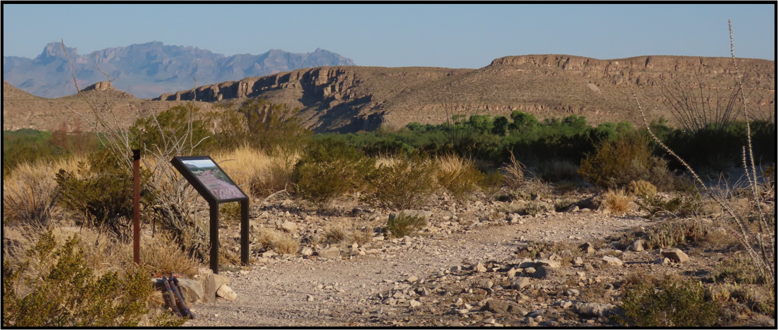 A sign in the desert with mountains in the background
