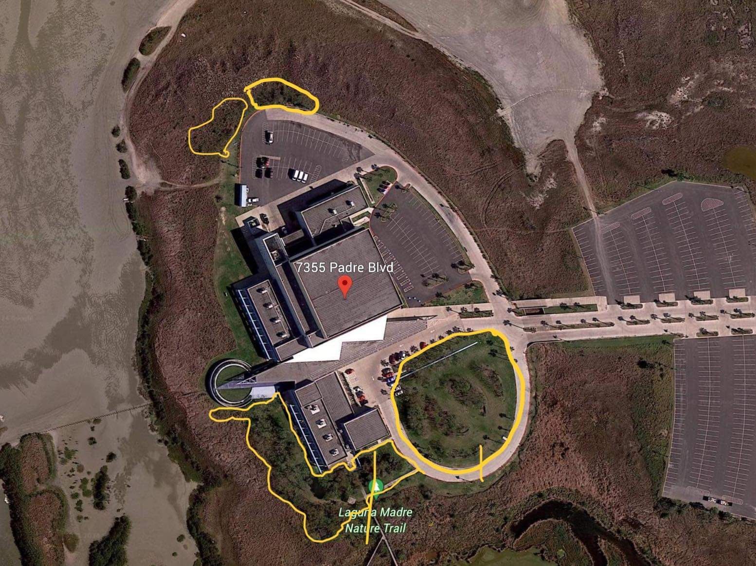 An aerial view of a large building with a lot of parking spaces surrounding it.