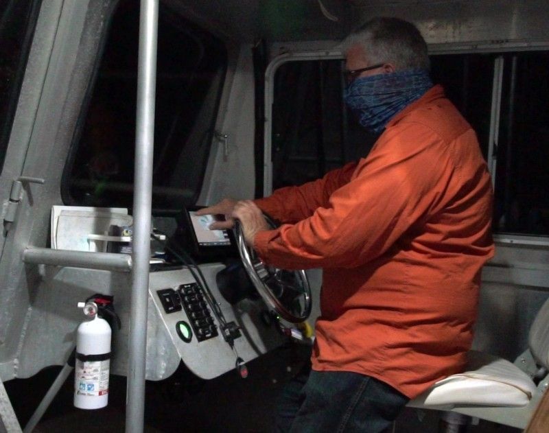 A man in an orange shirt is driving a bus