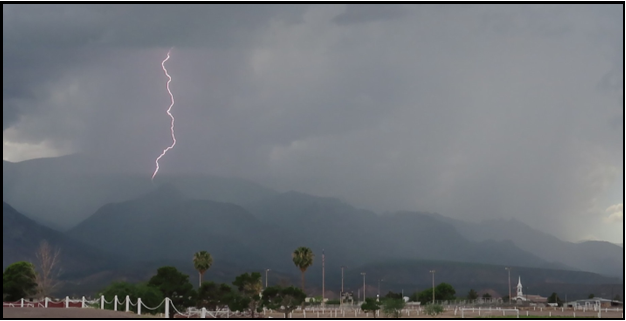 A picture of a lightning storm with mountains in the background