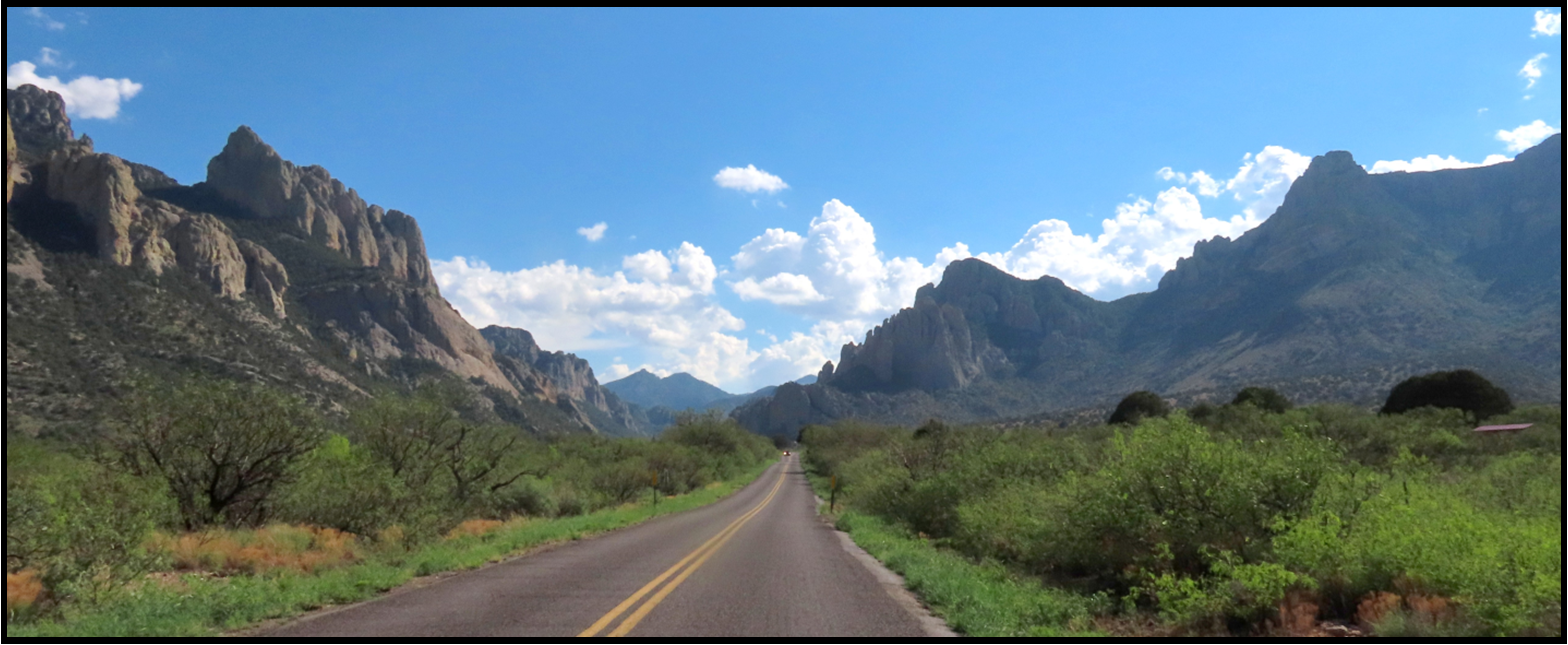 A road going through a valley with mountains in the background