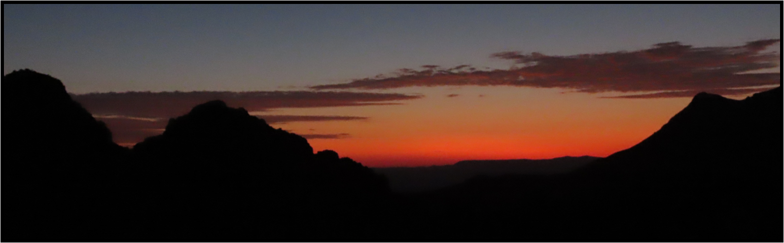 A sunset over a mountain range with a red sky