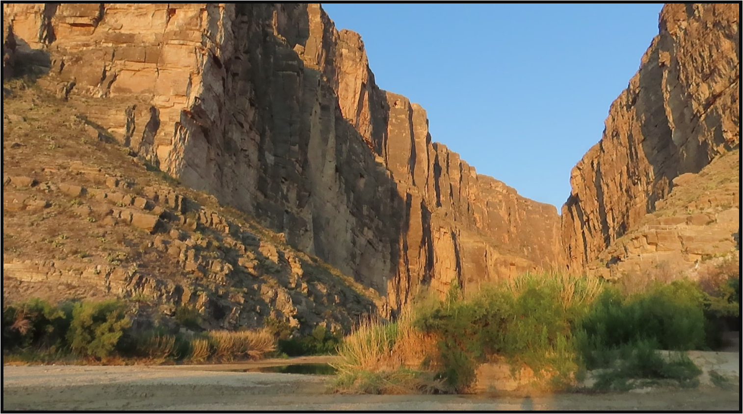 A river runs through a canyon with mountains in the background