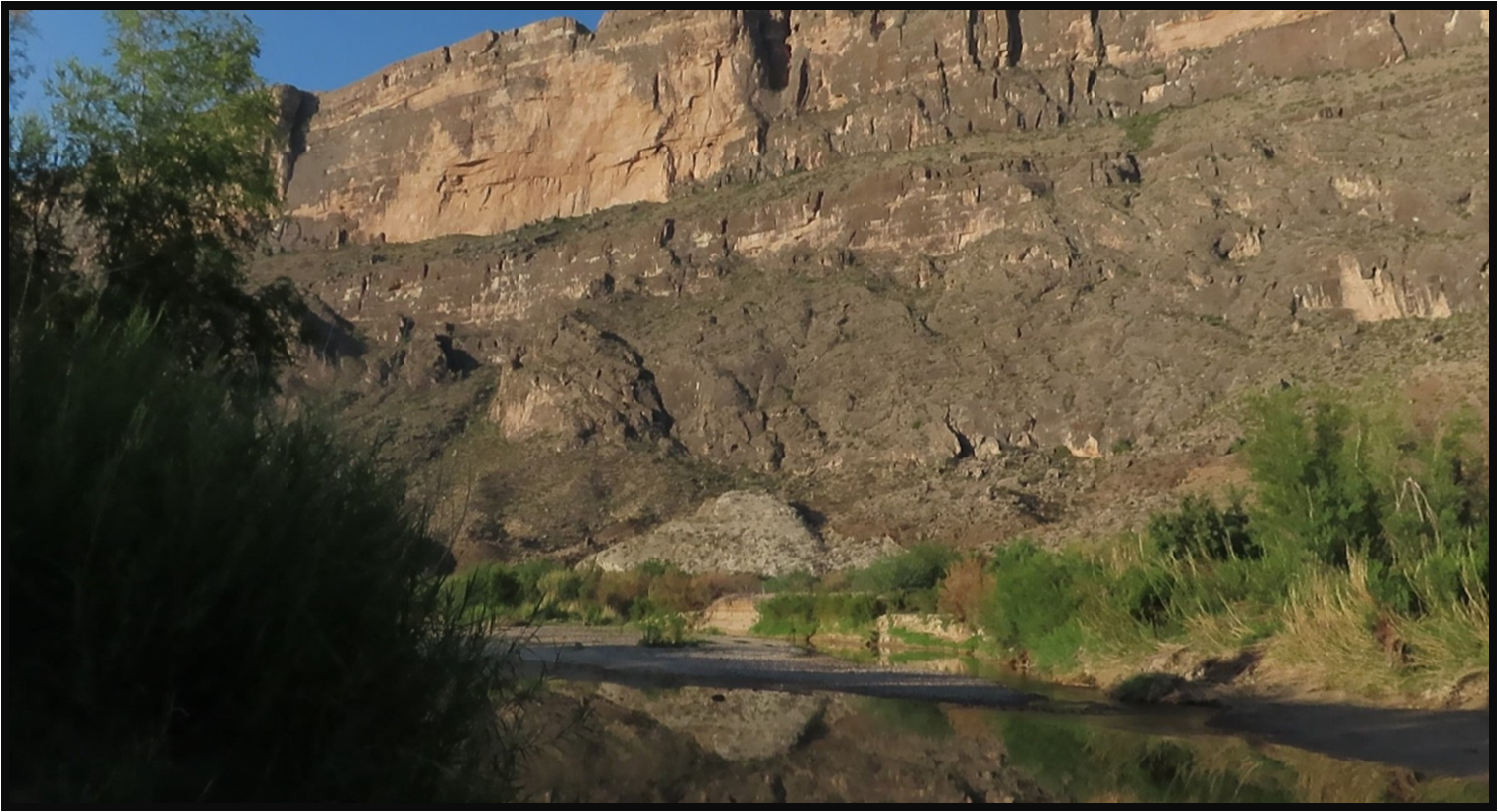 A river runs through a canyon with a mountain in the background