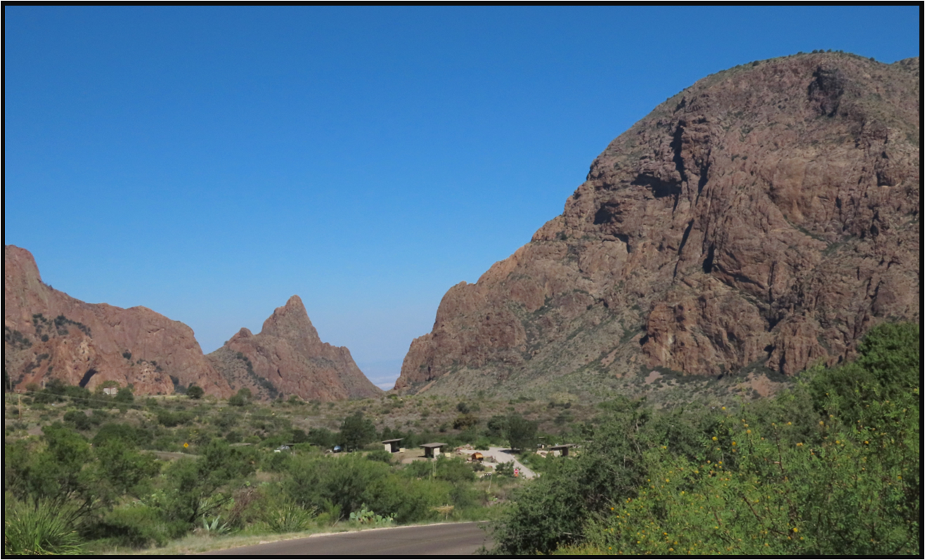 A road going through a canyon with mountains in the background