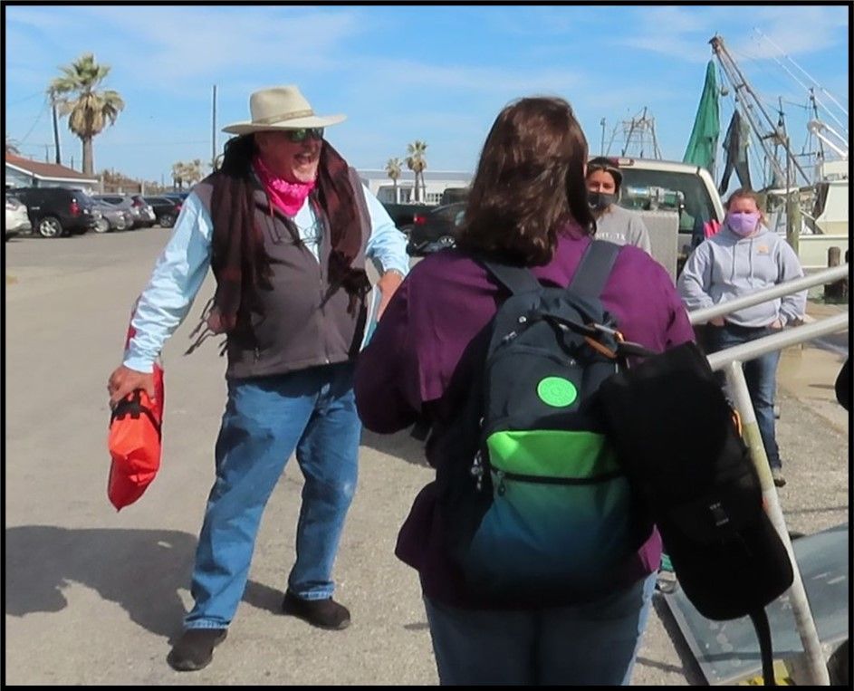 A man in a hat is talking to a woman with a backpack