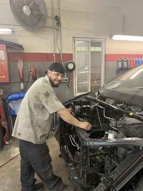 A man is working on the engine of a car in a garage