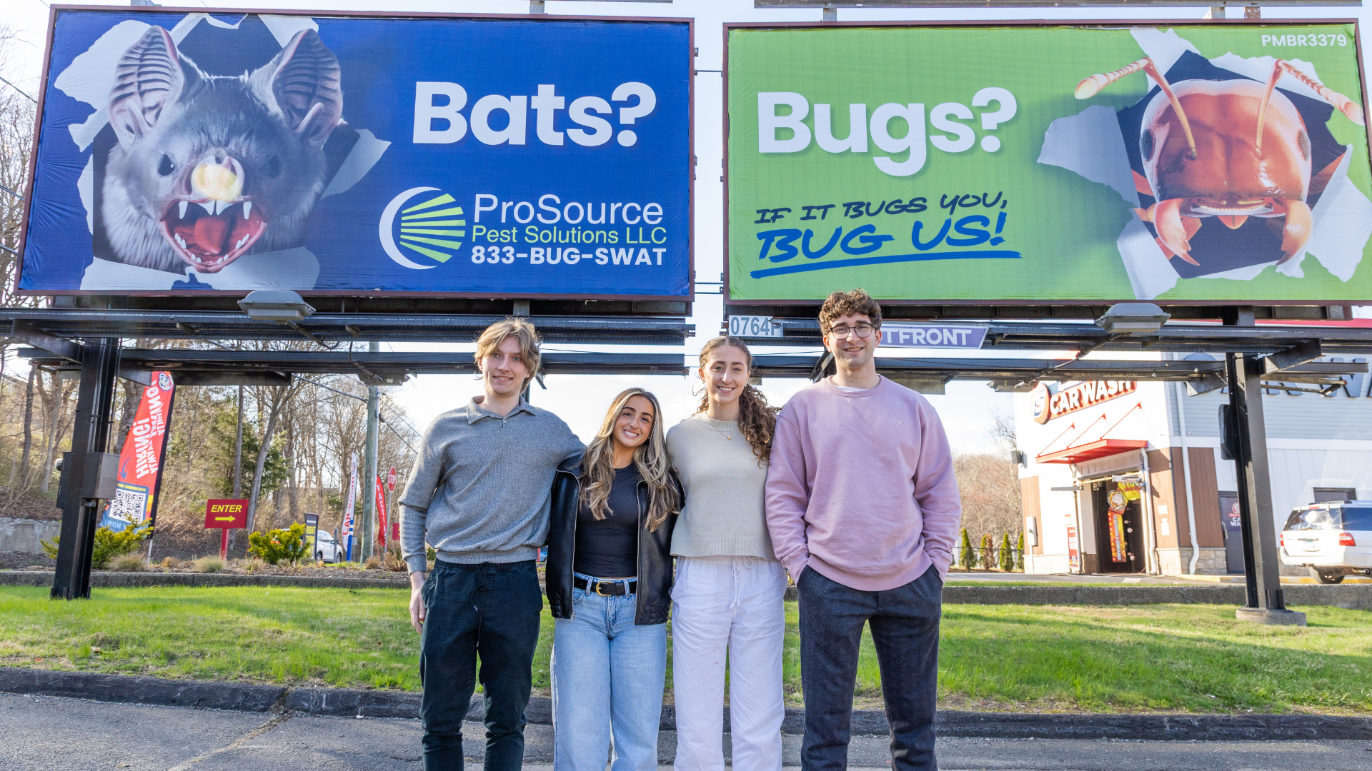 Four people stand under blue and green billboards reading “Bats?” and “Bugs?”