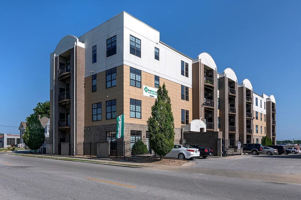 A large apartment building with cars parked in front of it.
