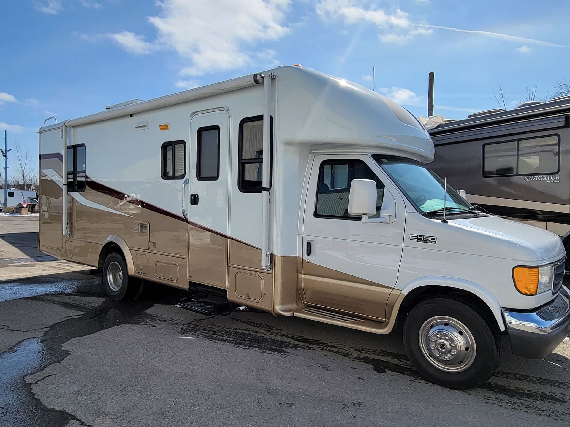 Un camping-car blanc et marron est garé dans un parking.