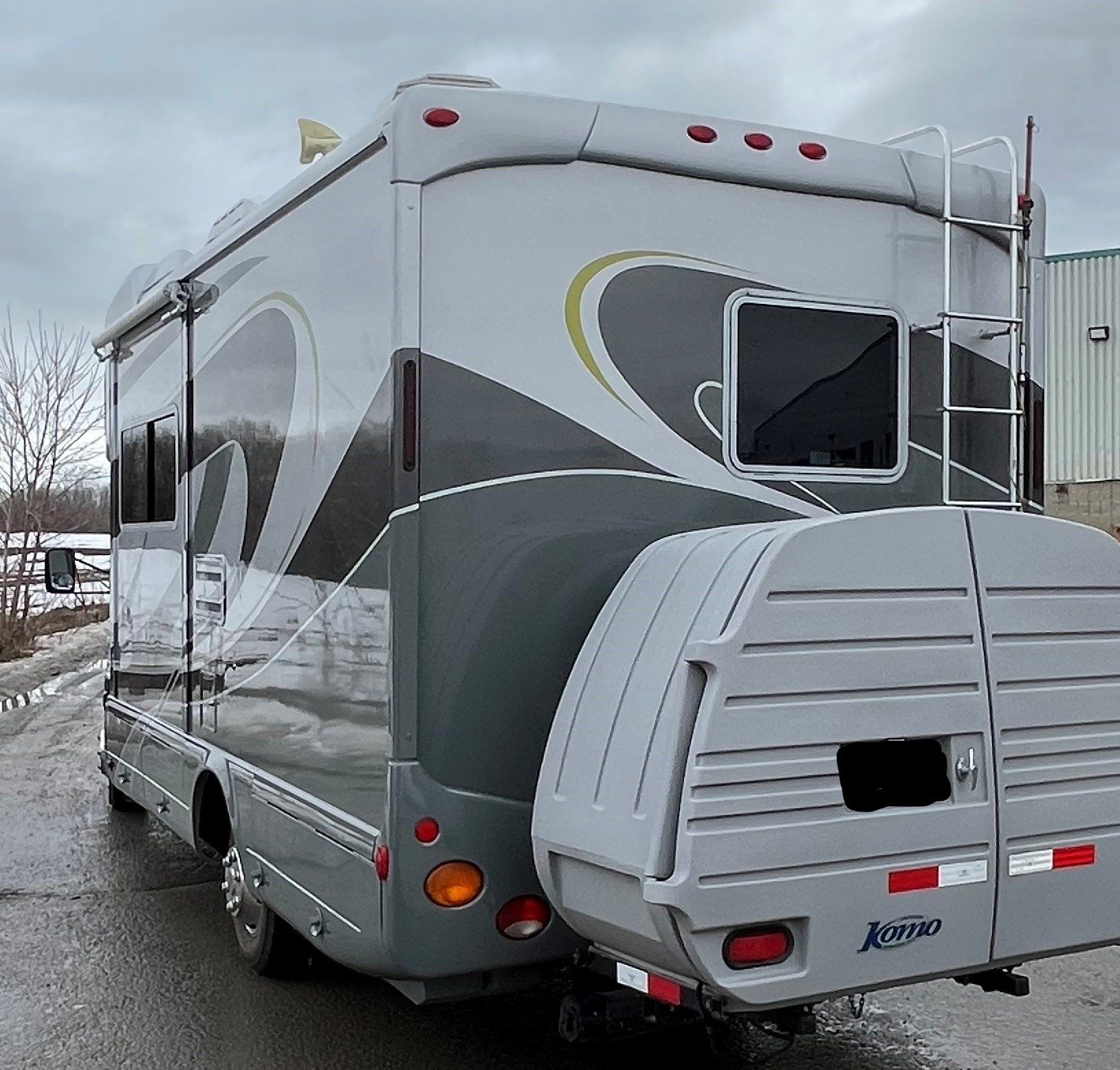 Un camping-car avec une remorque attachée est garé sur le bord de la route.
