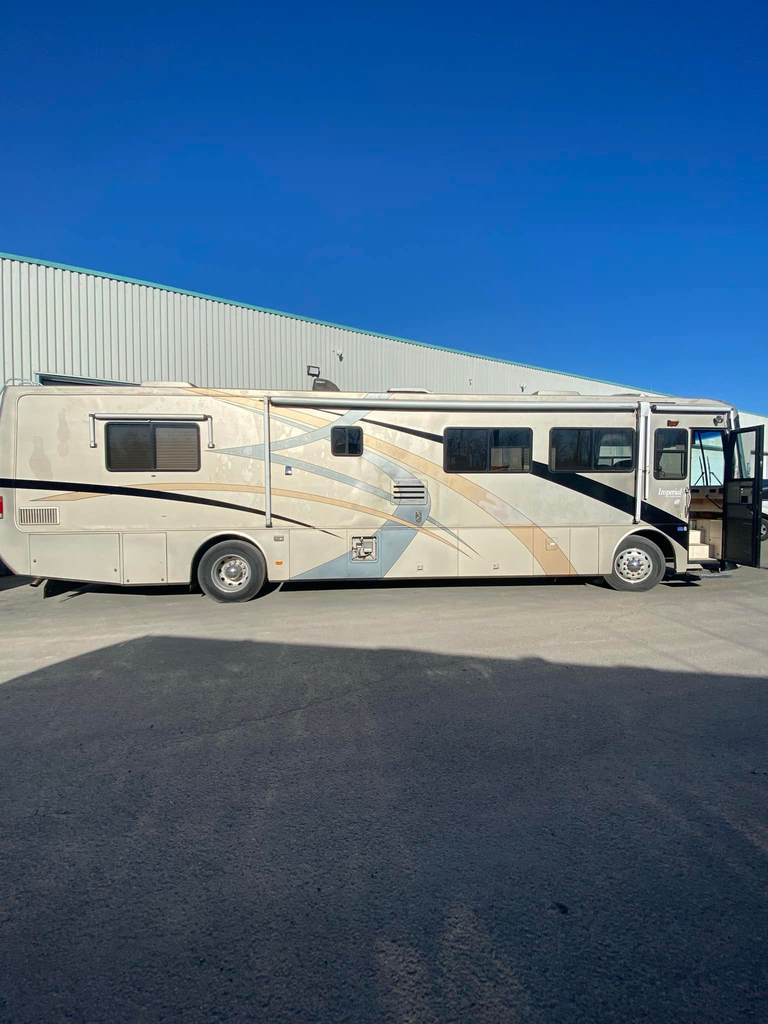 Un grand camping-car est garé sur un parking devant un immeuble.