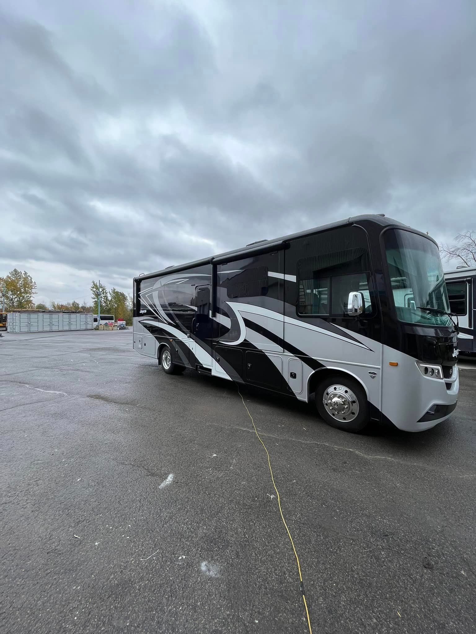 Un grand camping-car noir et blanc est garé dans un parking.