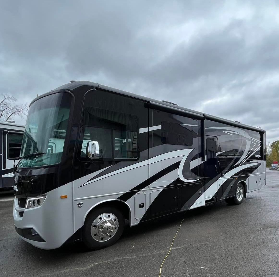 Un camping-car noir et blanc est garé dans un parking.