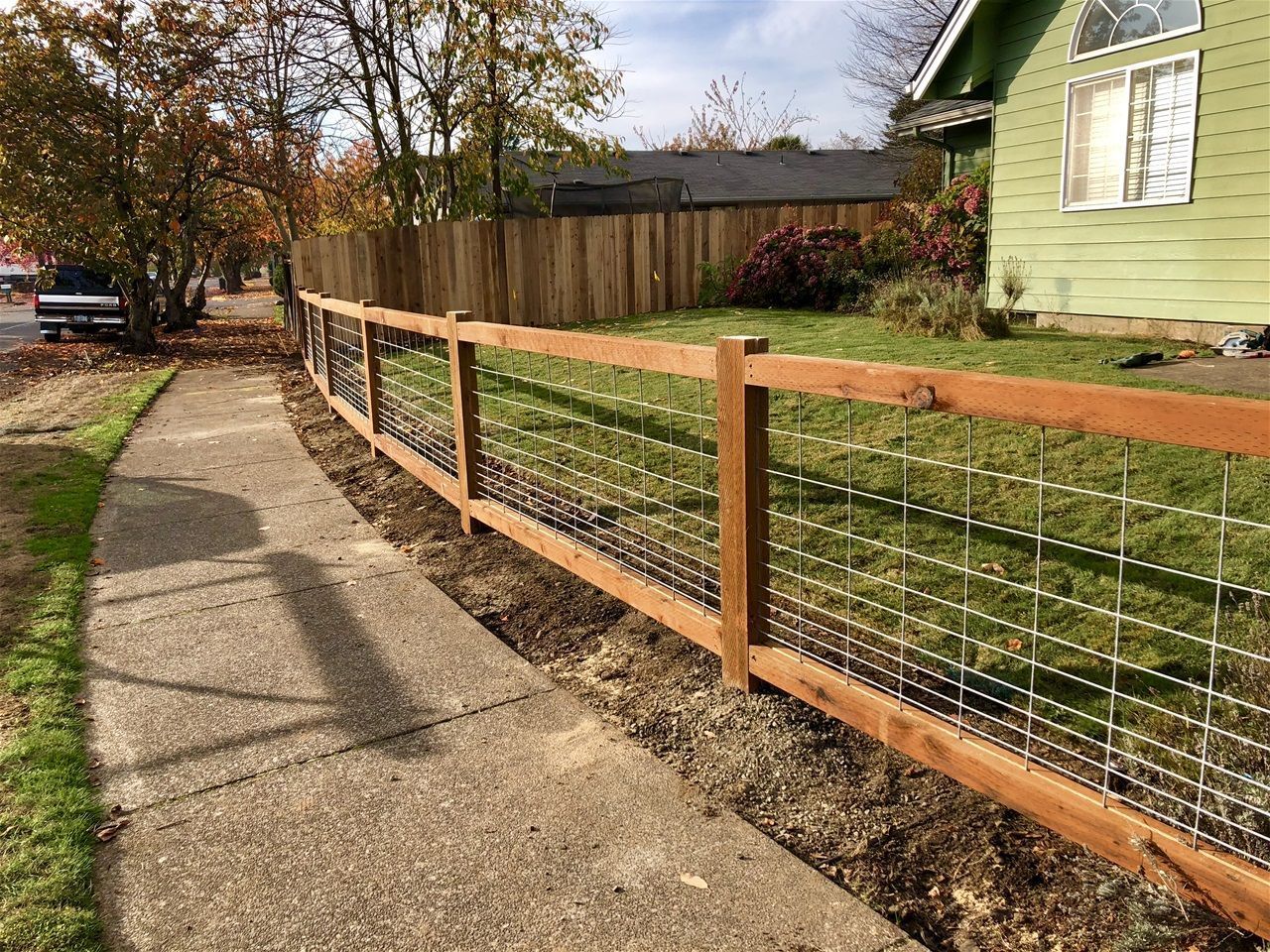 A wooden fence along a sidewalk next to a house.