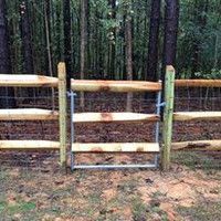 A wooden fence with a gate in the middle of the woods.