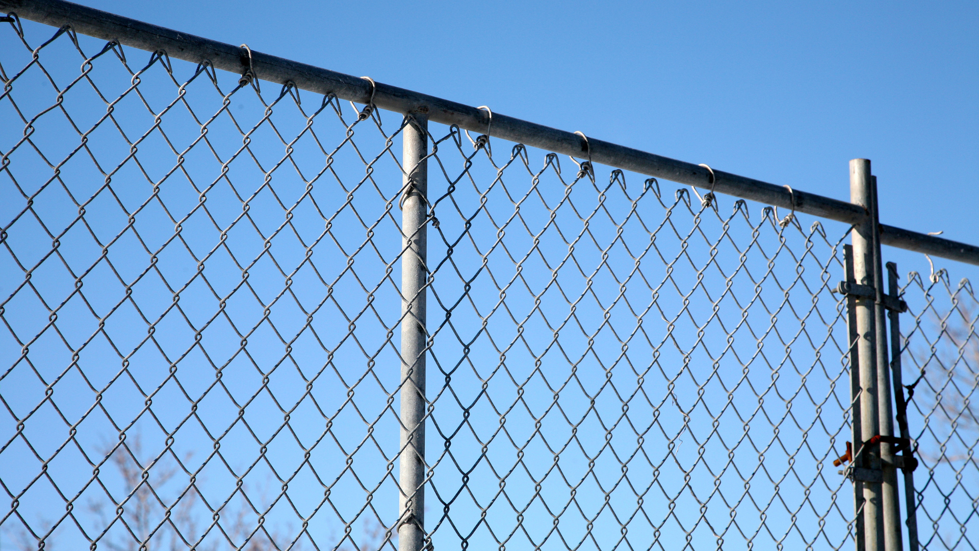 A chain link fence with a blue sky in the background