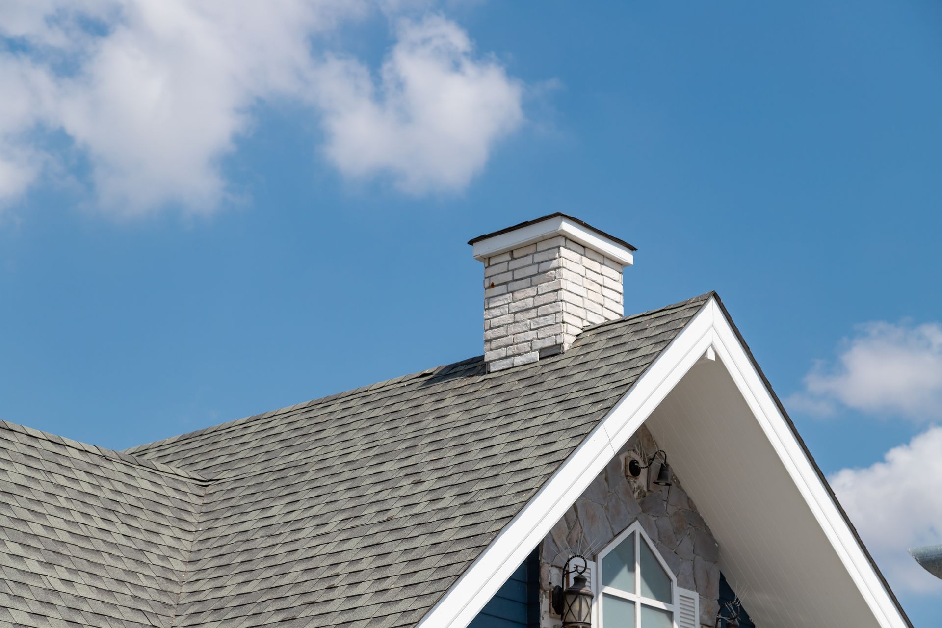 A house with a chimney on the roof and a blue sky in the background