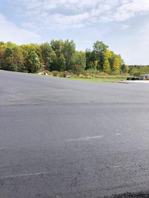 An empty parking lot with trees in the background