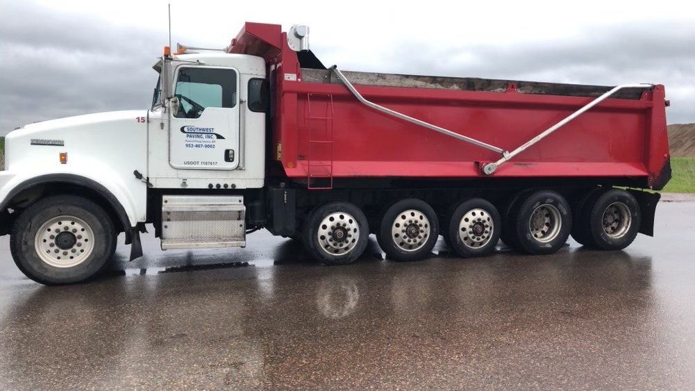 A red dump truck is parked on the side of the road