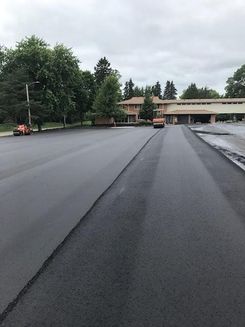A car is driving down a road with a house in the background