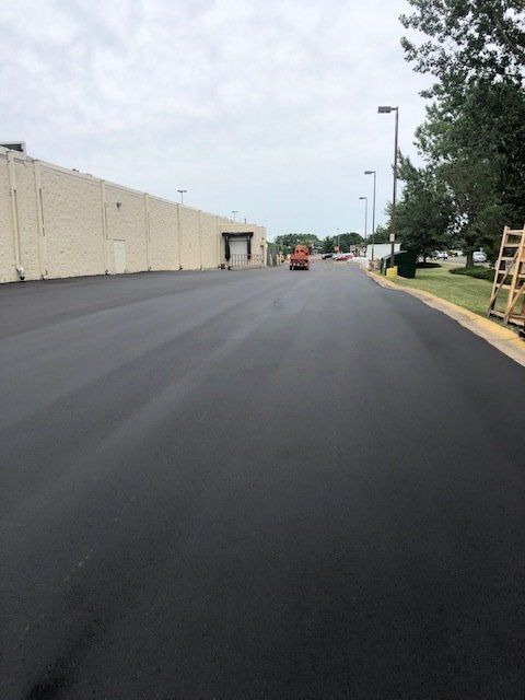 A black road with a white building in the background
