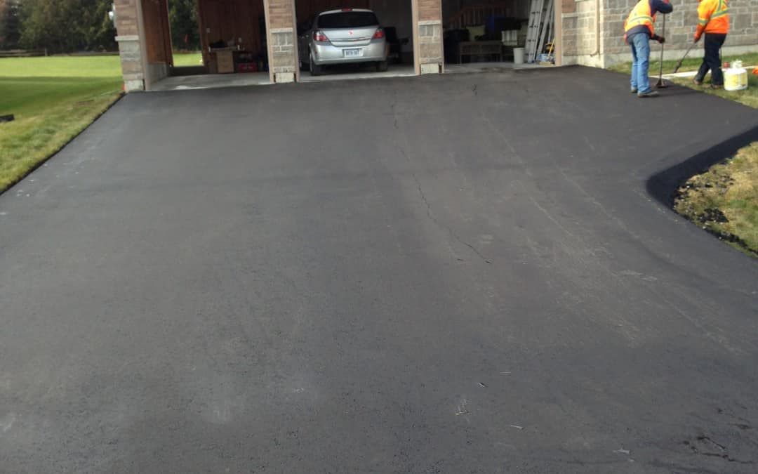 A car is parked in a driveway next to a garage.
