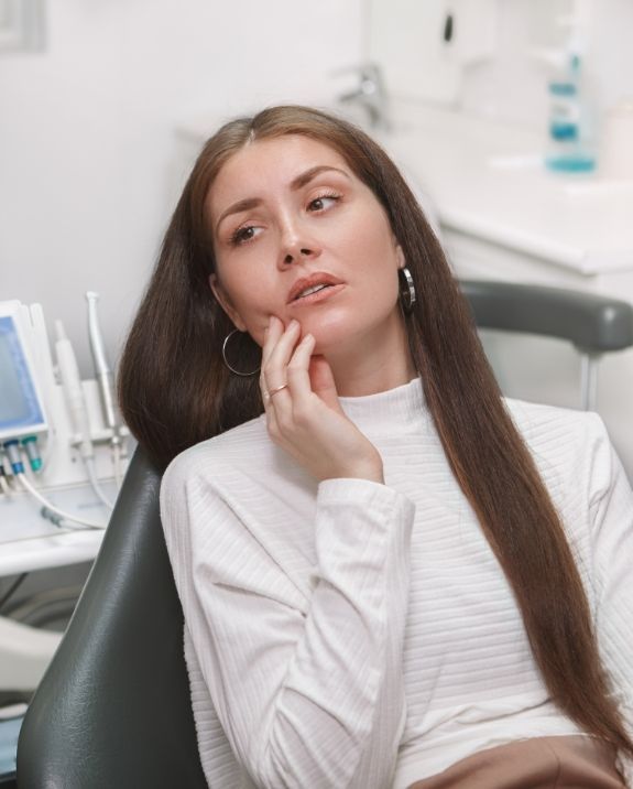 Dentist examining a patient's teeth with tools, the patient wearing protective glasses, indoor setting.