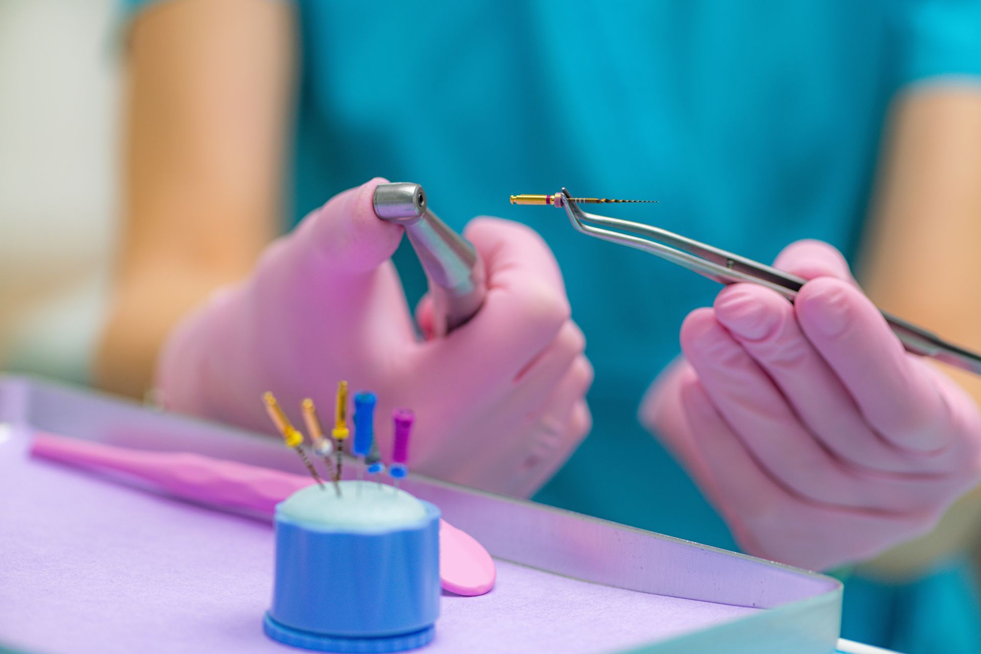 Dentist with gloved hands holding dental tools, preparing for a procedure.