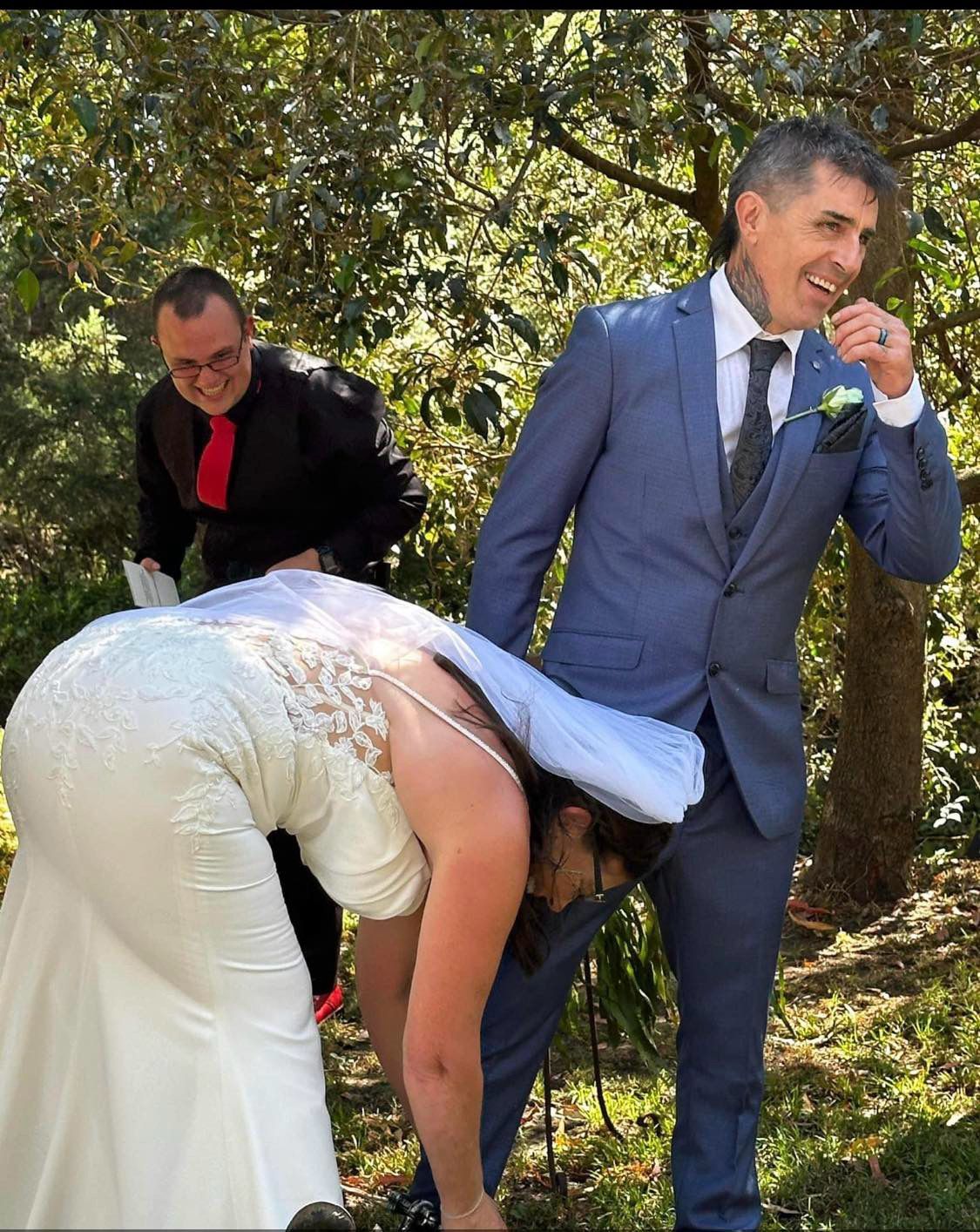 A bride and groom are posing for a picture in the woods.