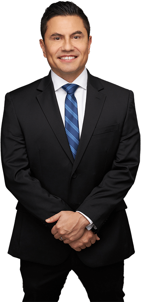 A person in a black suit, white dress shirt, and blue striped tie standing against a white background, smiling.