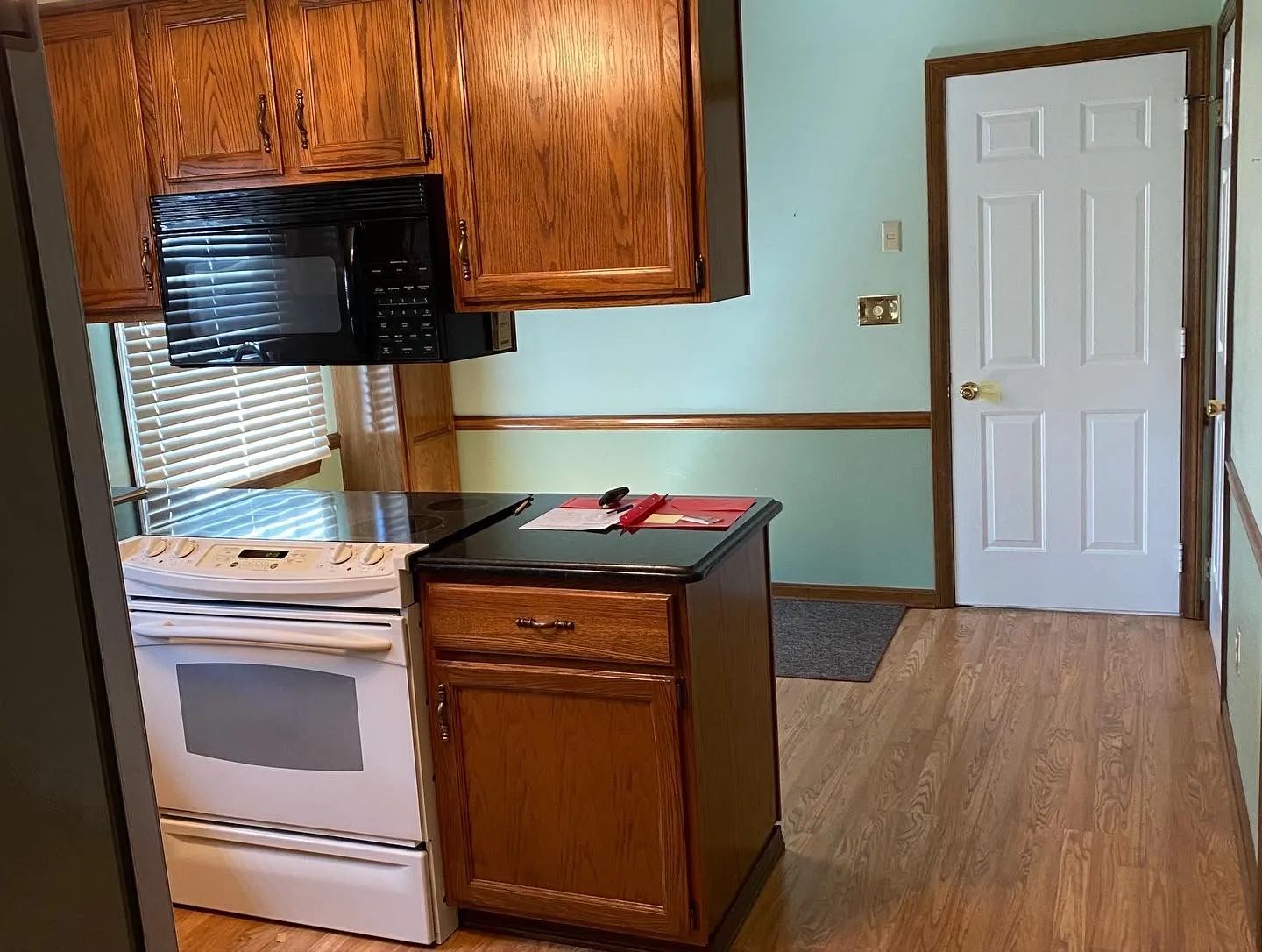 A kitchen with wooden cabinets and a white stove and microwave