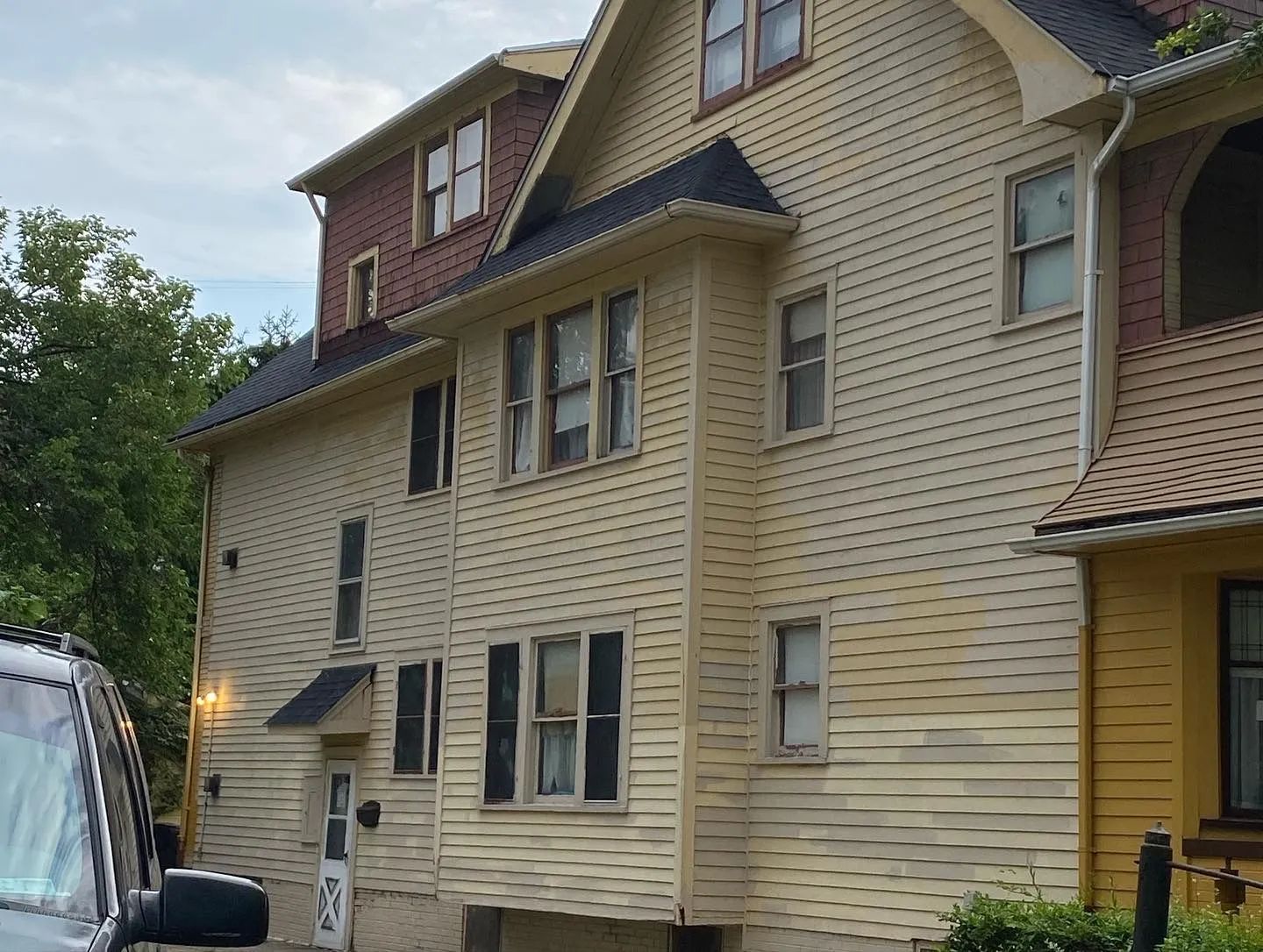 A car is parked in front of a large house