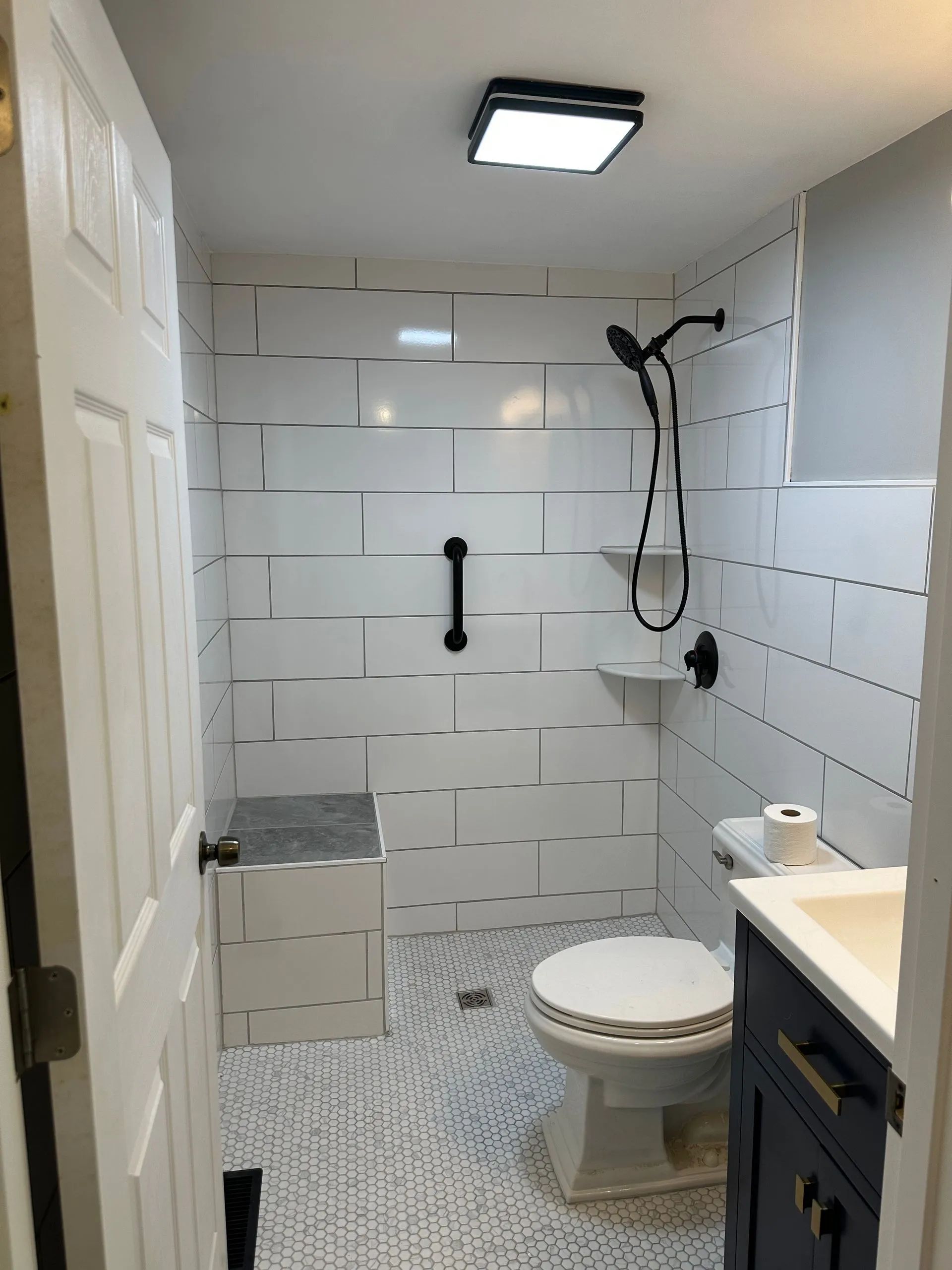 A bathroom with a toilet , sink and shower.