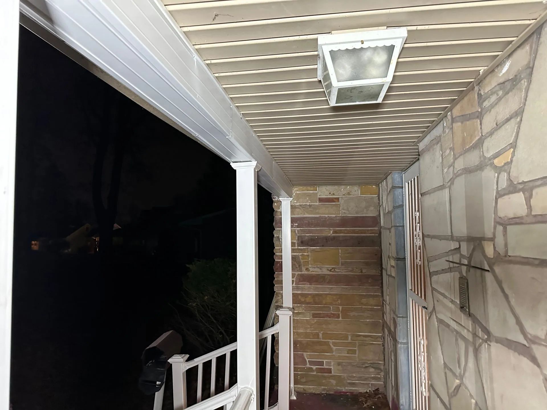 A porch with a white railing and a light on the ceiling.