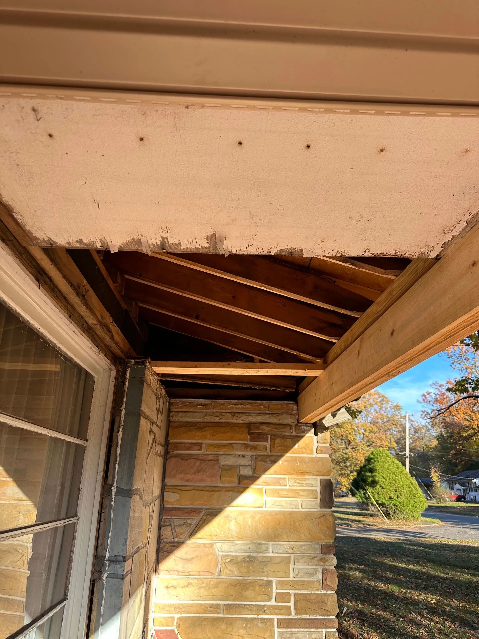 A porch with a wooden ceiling and a brick wall.