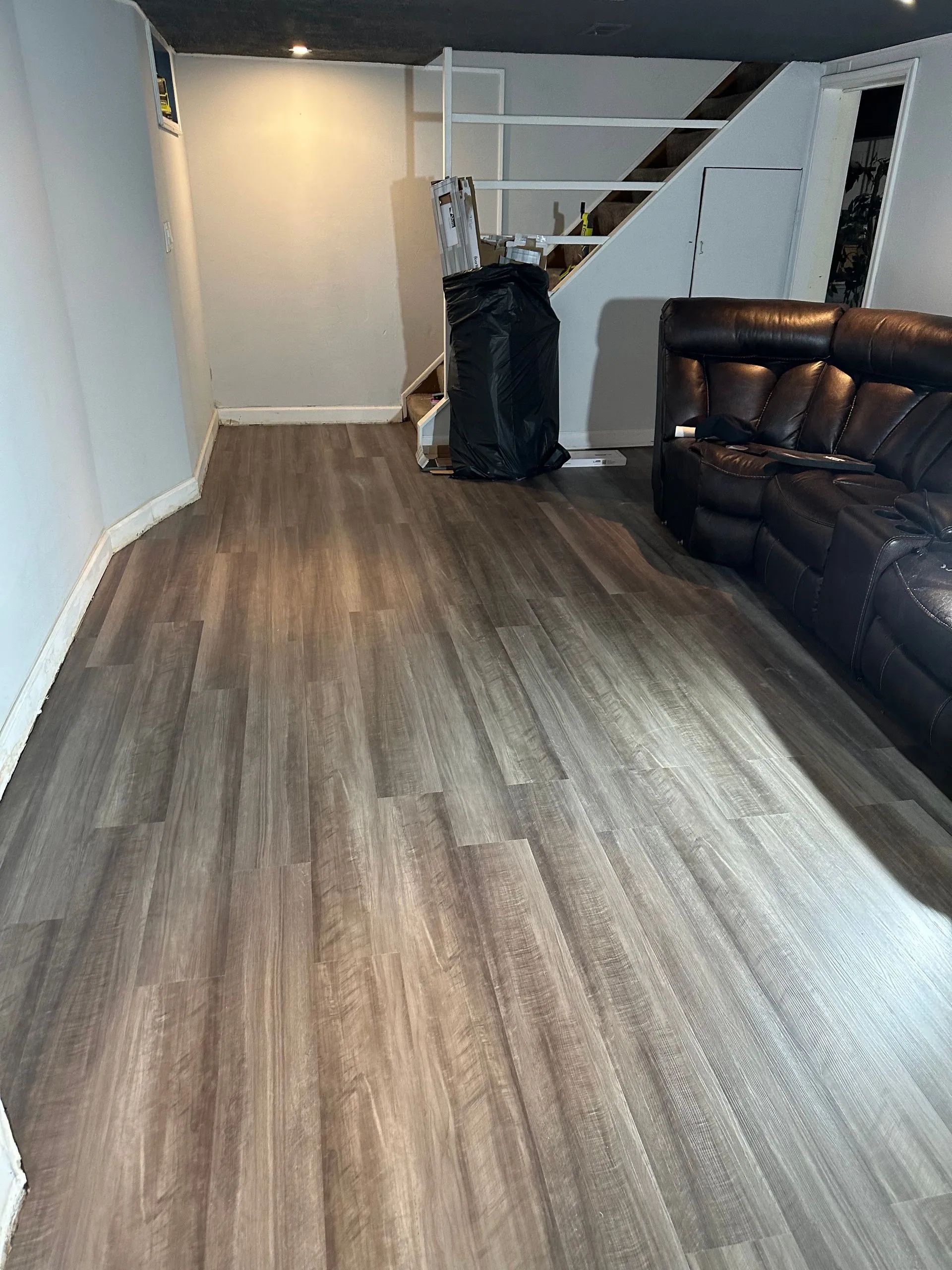 A living room with hardwood floors , a couch , and stairs.