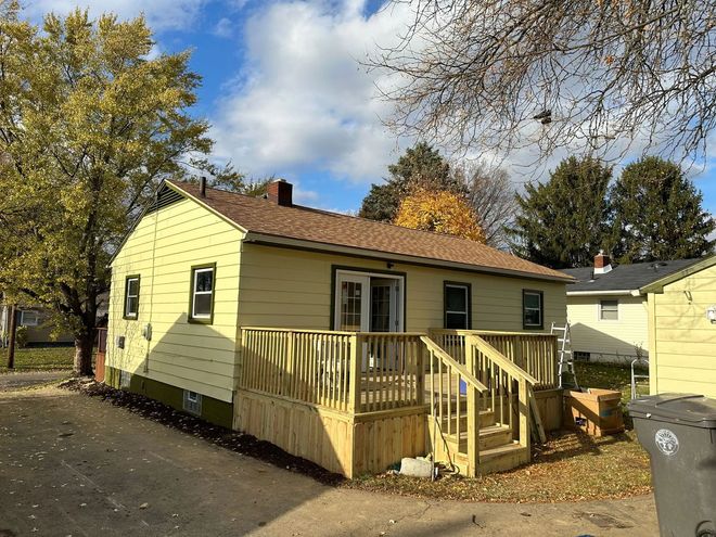 A yellow house with a wooden deck in front of it