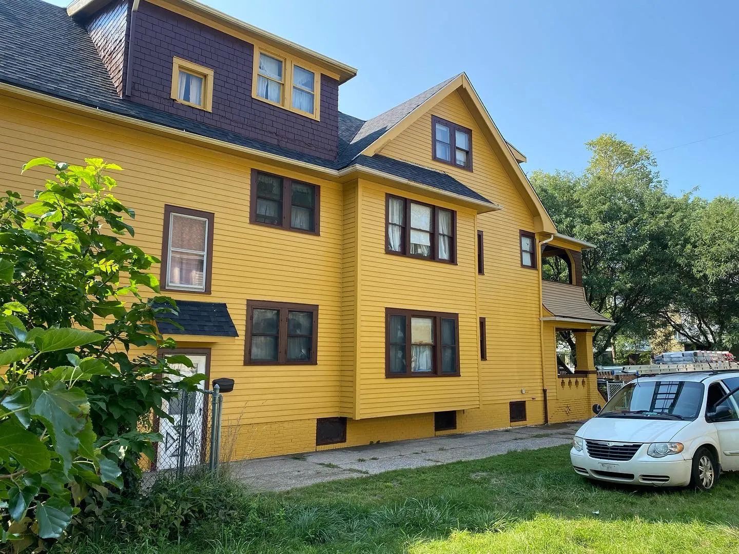 A yellow house with a white van parked in front of it.